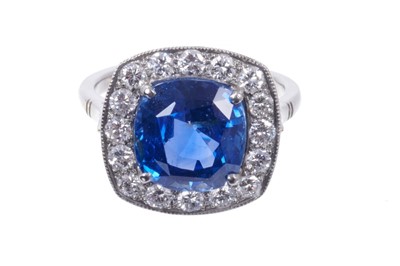 Lot 482 - Sapphire and diamond ring with a cushion cut natural blue sapphire weighing 5.82 carats, surrounded by sixteen brilliant cut diamonds in millegrain setting on plain shank. Ring size L. Accompanied...