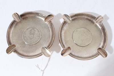 Lot 249 - Pair of Chinese silver ashtrays of circular form set with coins on a planished ground, marked Y C Levy, Sterling, all at approximately 5.5oz, 11.5cm in diameter