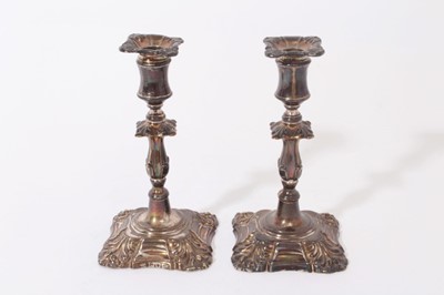 Lot 282 - Pair of Victorian silver taper sticks, with baluster stems and cotton reel candleholders in the Georgian style, on square bases with stylised scroll corners, separate sconces with