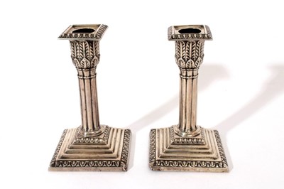 Lot 259 - Pair Edwardian silver candlesticks with fluted columns, candle holders with acanthus leaf decoration, separate sconces of square form, on square stepped bases