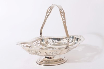 Lot 286 - George V silver cake basket of shaped oval form with pierced scroll decoration, and swing handle, raised on oval pedestal foot, (Birmingham 1922) Maker, Henry Clifford Davis, all at approximately 1...