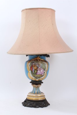 Lot 785 - Late 19th century French porcelain and bronze mounted oil lamp converted to electric lamp with painted romantic scene and floral reserve - with shade.