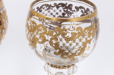 Lot 164 - Fine set of nine 19th century Bohemian glass goblets, the round bowls on hollow raspberry-prunted stems, on stepped feet, with raised gilt patterned decoration, 15.5cm height