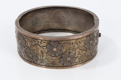 Lot 20 - Two Victorian silver hinged bangles, one with applied and textured floral design, Birmingham 1883, the other with engraved scenes depicting various boats in coastal bays
