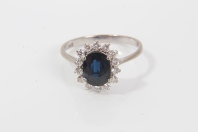 Lot 25 - Sapphire and diamond cluster ring with an oval mixed cut blue sapphire measuring approximately, surrounded by 14 brilliant cut diamonds in claw setting on 14ct gold shank