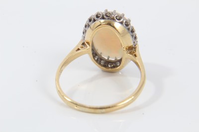 Lot 24 - Opal and diamond cluster ring with an oval cabochon opal surrounded by 20 single cut diamonds on 18ct gold shank