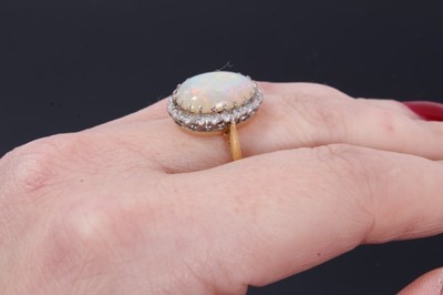 Lot 24 - Opal and diamond cluster ring with an oval cabochon opal surrounded by 20 single cut diamonds on 18ct gold shank