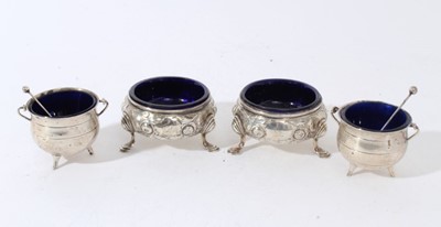 Lot 103 - Pair of George III silver salt cellars of cauldron from with embossed floral decoration, and blue glass liners, raised on three paw feet, (hallmarks rubbed) together with a pair of George V s