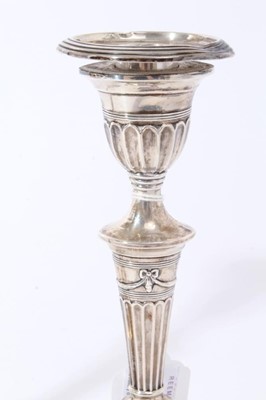Lot 37 - Pair of Victorian silver candlesticks with fluted tapering stems, urn-shaped candle holder with separate sconces, on fluted and reeded oval bases, (London 1895), 19cm in overall height