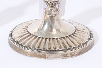 Lot 37 - Pair of Victorian silver candlesticks with fluted tapering stems, urn-shaped candle holder with separate sconces, on fluted and reeded oval bases, (London 1895), 19cm in overall height