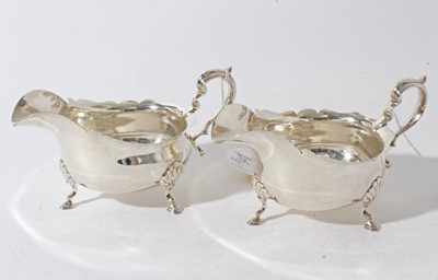 Lot 32 - Pair of Edwardian silver sauce boats of conventional form with scroll handles, each raised on three hoof feet, (London 1901) makers mark rubbed, all at approximately 10.5oz, 16cm from handle to spout.