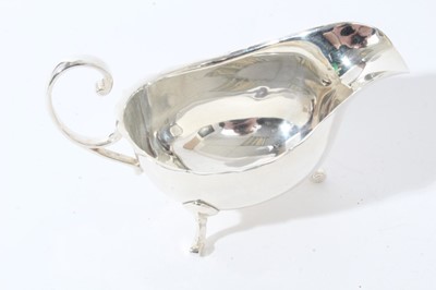 Lot 123 - George V silver sauce boat of helmet form with scroll handle, raised on three scroll feet, (Birmingham 1928) together with two pairs of silver napkin rings