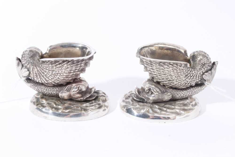 Lot 13 - Pair of 19th century cast white metal salts  in the form of a nautilus shell on the back of a dolphin, on a wave pattern oval base, possibly an Elkington electrotype, 9.5cm overall width