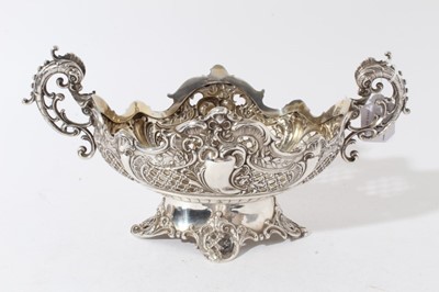 Lot 178 - Edwardian silver table centre of oval form with embossed and pierced decoration with twin handles modelled as classical Dolphins, raised on and oval foot with four scroll feet, (London 1901)