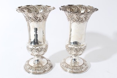 Lot 16 - Pair of Edwardian silver spill vases, with embossed decoration scroll decoration and flared rims, raised on circular pedestal (Sheffield 1902)