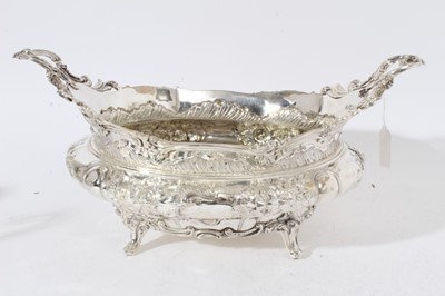 Lot 225 - Impressive Edwardian silver table centre bowl of oval form with embossed floral and scroll decoration twin scroll handles and raised on four scroll feet, (London 1901)