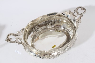 Lot 225 - Impressive Edwardian silver table centre bowl of oval form with embossed floral and scroll decoration twin scroll handles and raised on four scroll feet, (London 1901)