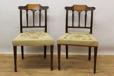 Lot 1469 - Pair of late 18th century Sheraton inlaid mahogany dining chairs, with shaped scroll top rail above reeded pilasters, needlework seats and square taper legs with spade feet