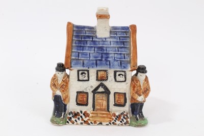 Lot 38 - Early 19th century Staffordshire Prattware money box, modelled as a house with figures on either side and faces peering out of the windows