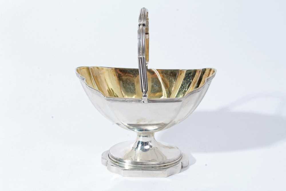 Lot 15 - George III silver sugar basket of navette form with reeded borders, swing handle and gilded interior, raised on pedestal foot, (London 1797), maker Thomas England, all at 6.5oz, 13.3cm in length
