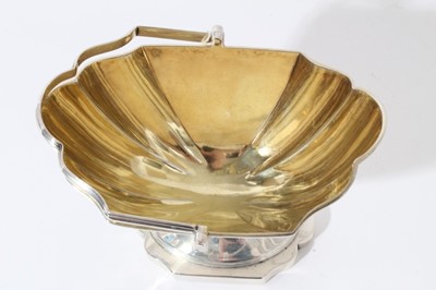 Lot 15 - George III silver sugar basket of navette form with reeded borders, swing handle and gilded interior, raised on pedestal foot, (London 1797), maker Thomas England, all at 6.5oz, 13.3cm in length