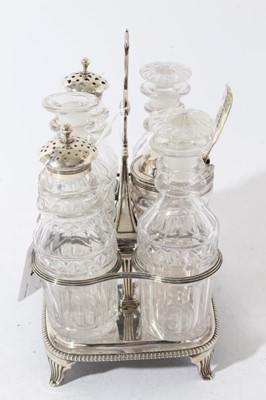 Lot 64 - George III silver cruet frame of rectangular form with reeded decoration and central handle, on four fluted feet, with six matching cut glass condiment bottles, including three with silver mounts.