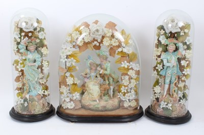 Lot 321 - A trio of Edwardian glass domes containing decorative figure groups among silk flowers