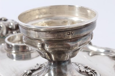 Lot 157 - Victorian silver inkstand of oval form, with shell, scroll and leaf border, central chamberstick with snuffer and a pair of cut glass inkwells with silver mounts, on four scroll feet (London 1891)