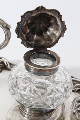 Lot 157 - Victorian silver inkstand of oval form, with shell, scroll and leaf border, central chamberstick with snuffer and a pair of cut glass inkwells with silver mounts, on four scroll feet (London 1891)