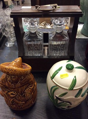 Lot 304 - Two bottle tantalus together with two ceramic storage jars (3)