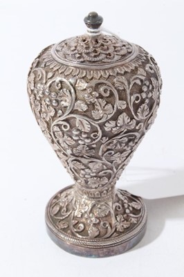 Lot 140 - Pair of good quality late 19th century Indian white metal pepperettes of ovoid form with ornate vine leaf decoration in relief, on circular feet with screw in covers to bases
