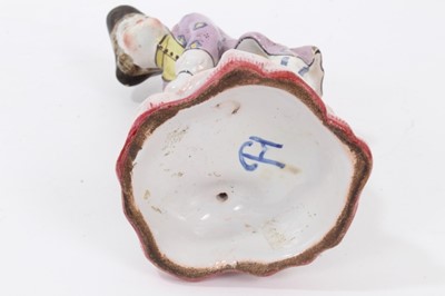 Lot 102 - 19th century French faience figure of a boy tying his shoelaces, wearing tricorn hat, lilac floral jacket, yellow shirt, and blue and white striped breeches, mark on the base for Theodore Deck, 16....
