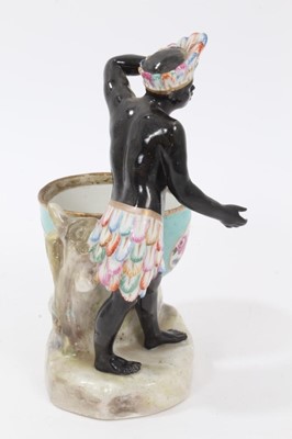 Lot 98 - Late 19th century Dresden figural porcelain sweetmeat, emblematic of Africa, the male figure shown wearing feather headdress and skirt, holding a lemon, the bowl painted with panels of flowers and...