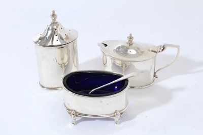 Lot 119 - George V silver three piece cruet set comprising mustard pot of oval form with domed hinged cover, blue glass liner and angular handle together with matching pepperette and salt cellar (Sheffield 1...