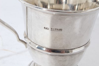Lot 133 - George V silver christening mug of tapered form with central reeded band, with scroll handle, on a circular foot, (Birmingham 1935), together with two other silver christening mugs (various dates a...