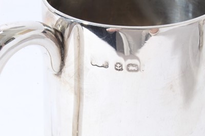 Lot 133 - George V silver christening mug of tapered form with central reeded band, with scroll handle, on a circular foot, (Birmingham 1935), together with two other silver christening mugs (various dates a...