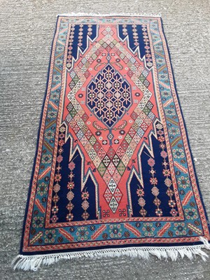 Lot 1064 - Eastern rug with geometric decoration on red and blue ground, 203cm x 97cm