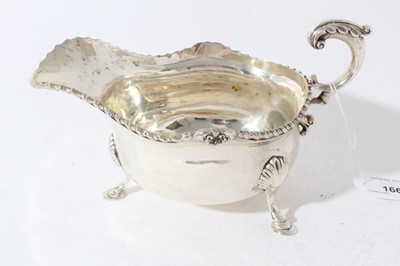Lot 166 - George V silver sauce boat of conventional form with gadrooned border and scroll handle raised on three paw feet, (Chester 1912), 12.5oz, 22cm in length
