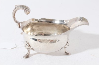 Lot 200 - George II silver sauce boat of conventional form with engraved armorial, scroll handle, raised on three hoof feet, (London 1748), maker John Pollock, all at approximately 12oz, 19cm in length