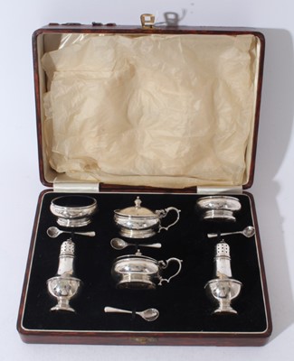 Lot 207 - George V silver six piece cruet set comprising two mustard pots of cauldron form with blue glass liners on circular feet, together with two matching pepperettes and two matching salt cellars, and f...