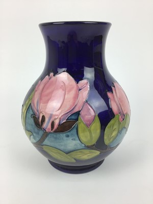 Lot 66 - Moorcroft pottery vase decorated in the Magnolia pattern on blue ground, impressed marks and green painted signature to base, 25cm high