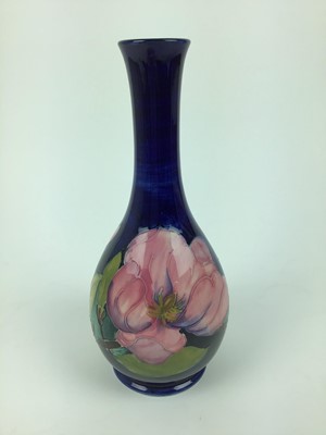 Lot 68 - Moorcroft pottery slender neck vase decorated in the Magnolia pattern on blue ground, impressed marks and green painted signature to base, 27cm high