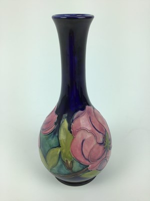 Lot 69 - Moorcroft pottery slender neck vase decorated in the Magnolia pattern on blue ground, green painted signature to base, 21.5cm high
