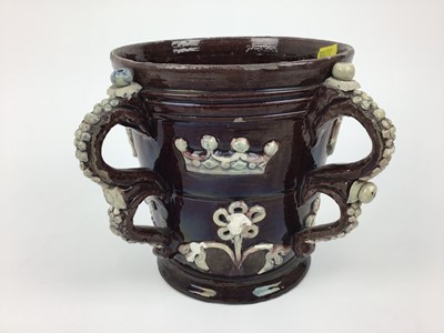 Lot 77 - Castle Hedingham pottery four handled loving cup with applied 1650 and floral decoration on brown ground, 18cm high
