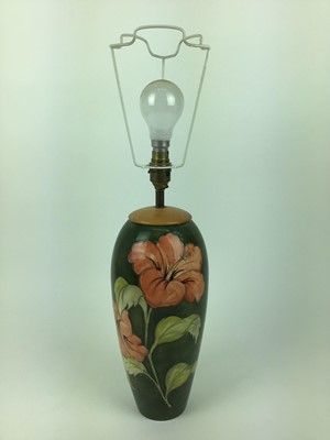 Lot 598 - Moorcroft pottery table lamp decorated in the Hibiscus pattern on green ground, impressed marks to base and original paper label - Potters To The Late Queen Mary, 31.5cm high excluding the fittings