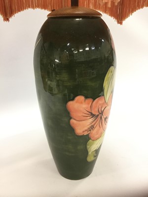 Lot 598 - Moorcroft pottery table lamp decorated in the Hibiscus pattern on green ground, impressed marks to base and original paper label - Potters To The Late Queen Mary, 31.5cm high excluding the fittings