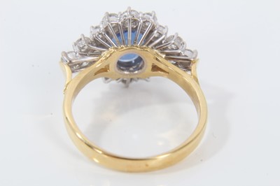 Lot 28 - Sapphire and diamond cluster ring with an oval mixed cut blue sapphire measuring approximately 9.5mm x 7.7mm x 3.3mm surrounded by twelve brilliant cut diamonds with a further six diamonds to the s...