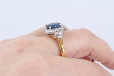 Lot 28 - Sapphire and diamond cluster ring with an oval mixed cut blue sapphire measuring approximately 9.5mm x 7.7mm x 3.3mm surrounded by twelve brilliant cut diamonds with a further six diamonds to the s...