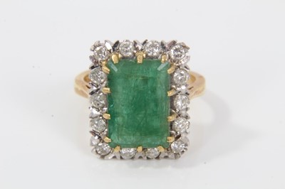 Lot 32 - Emerald and diamond cluster ring with a rectangular step cut emerald measuring approximately 12.85mm x 8.75mm x 5mm, surrounded by a border of brilliant cut diamonds in claw setting on 18ct gold sh...