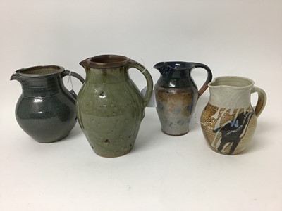 Lot 221 - Four salt glazed studio pottery jugs by John Jelfs with green glaze, 19.5cm, Toff Milway with blue glaze, 16.5cm, Rosemary Cochrane with brown and cream glaze, 14.5cm and Sylvia Dales, 17cm high